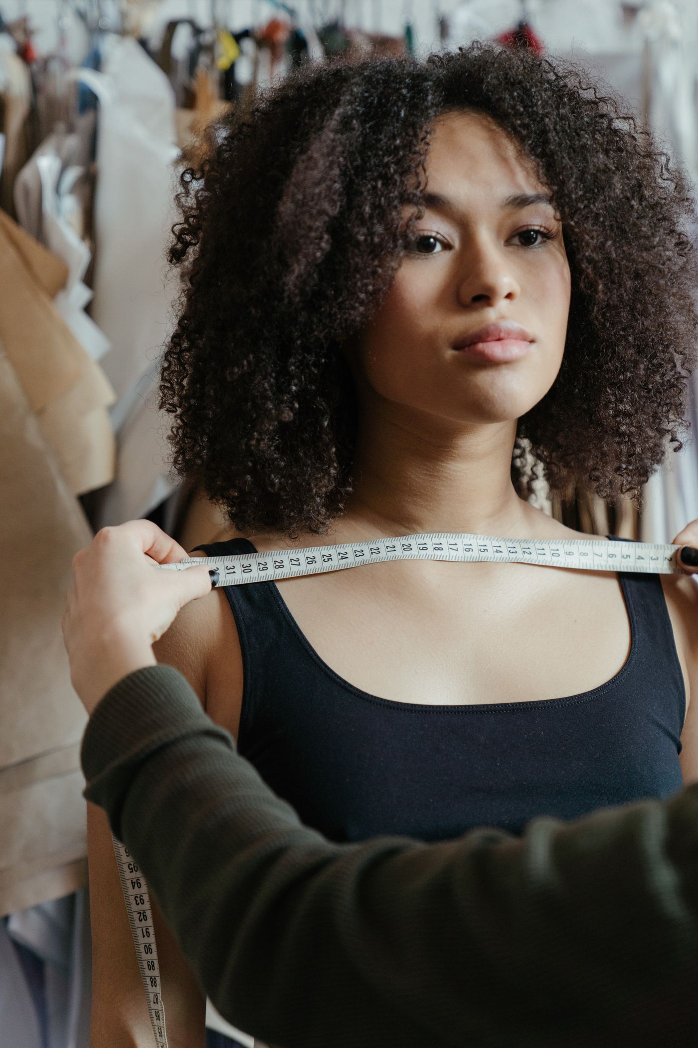 A tailor measuring across the shoulders with a tape measure