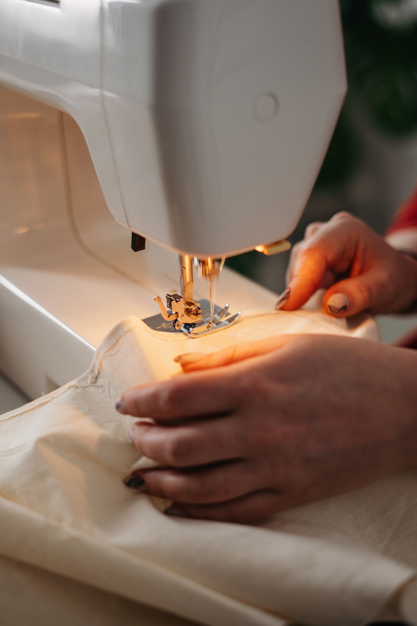Hands guiding fabric under a sewing-machine needle