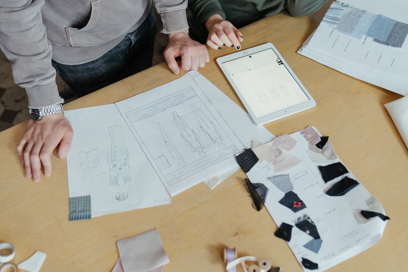 A work table with fabric swatches, a sketch, and a tablet