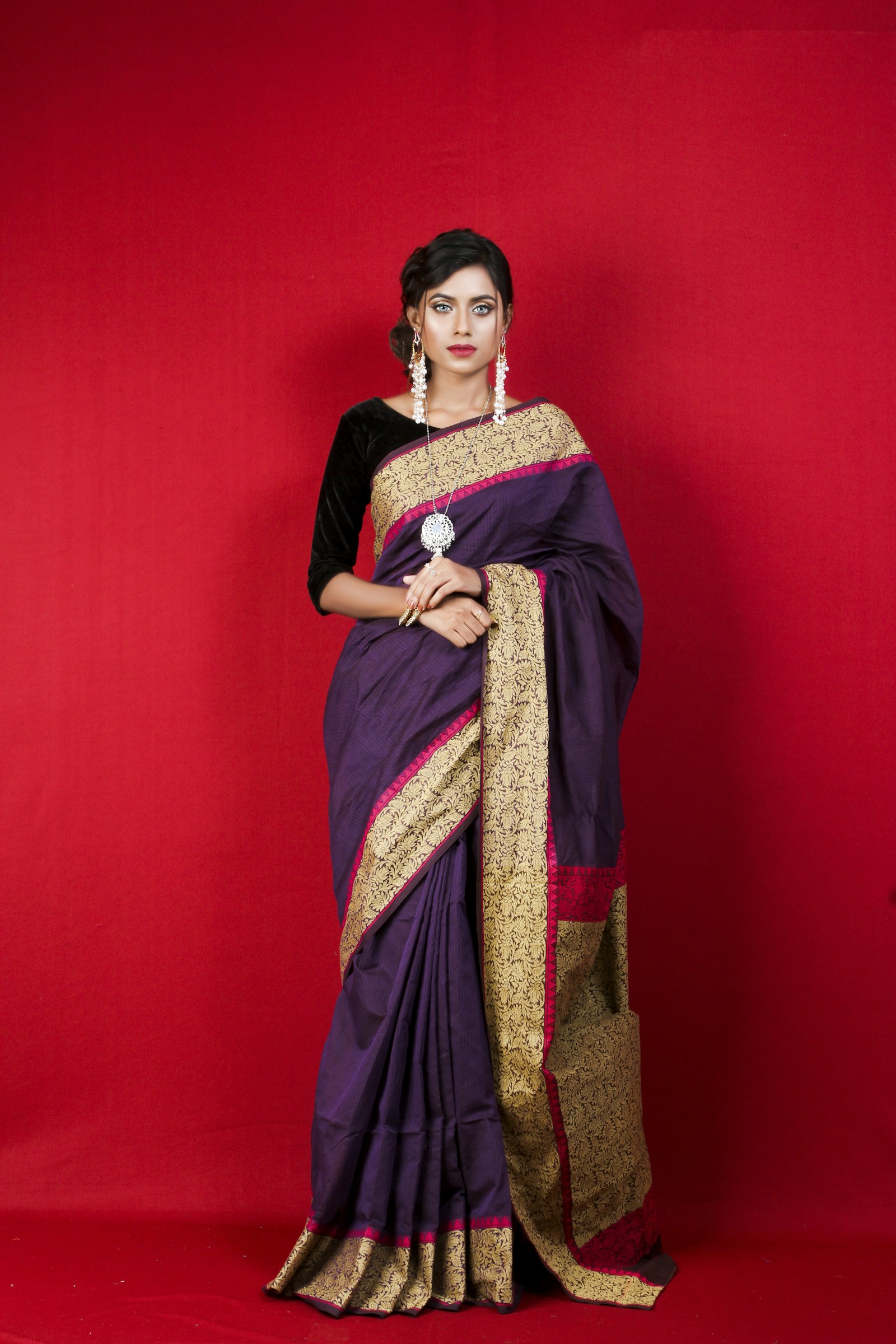 Studio portrait of a woman wearing a purple saree with a gold border